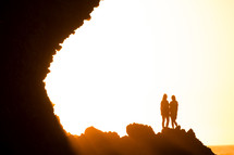 silhouettes of women standing at the edge of a cliff 