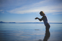 a woman wading and playing in water 