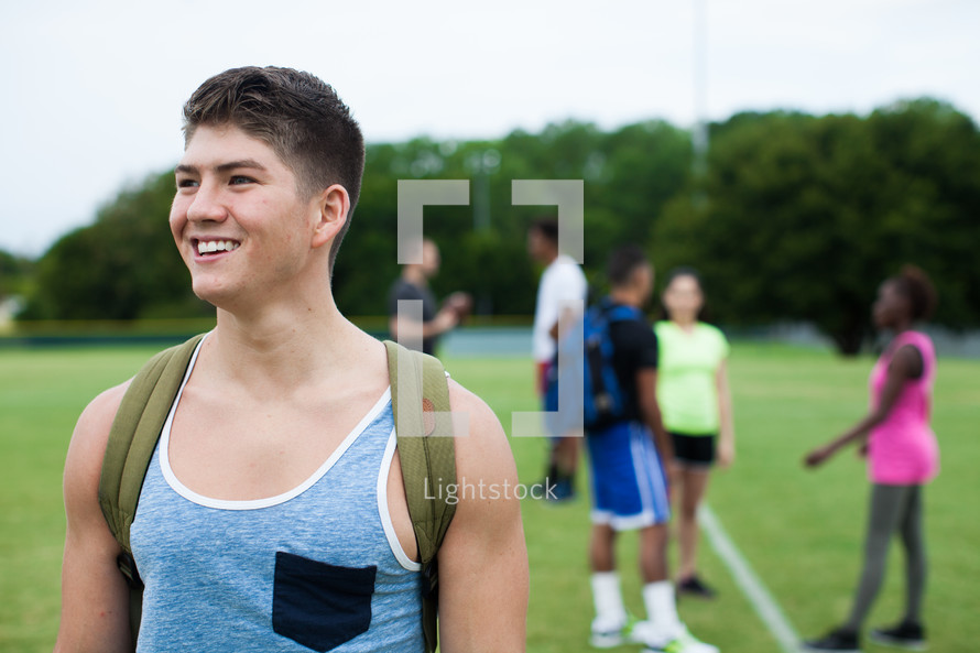 an athlete with a backpack standing on a sports field at practice 