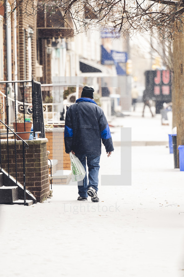 a man walking on a sidewalk in the snow 