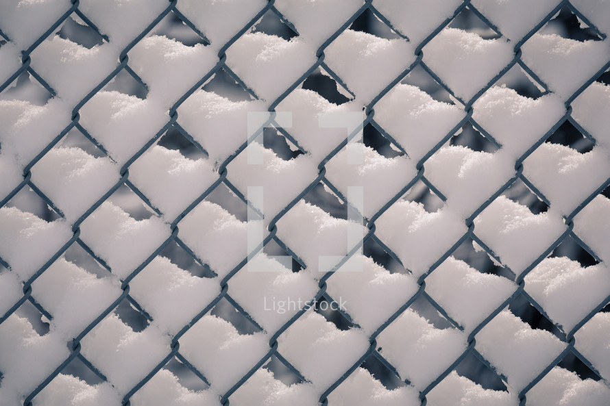 snow on a chain link fence 