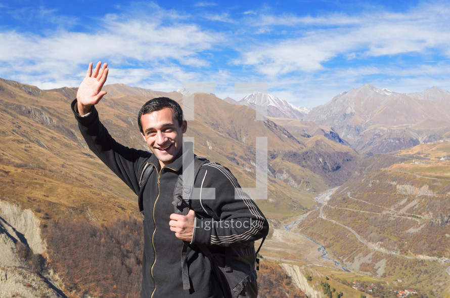 man waving on top of a mountain 