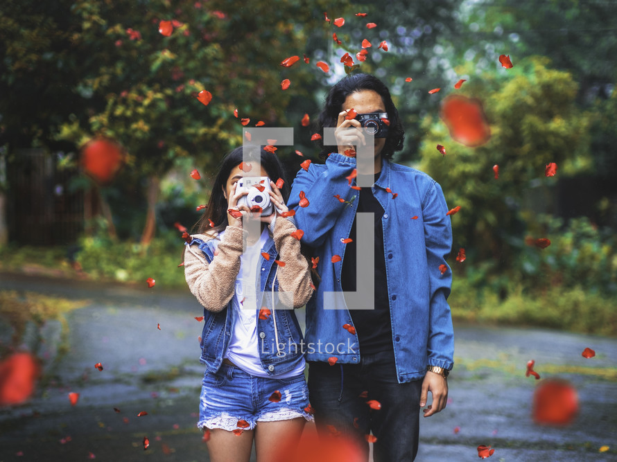 a couple holding camera and falling rose petals 