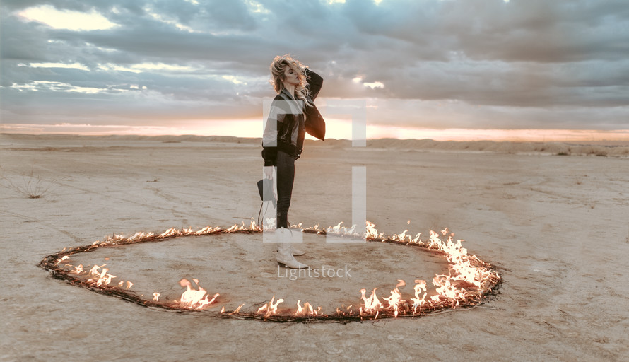 a female standing in a ring of fire in a desert 