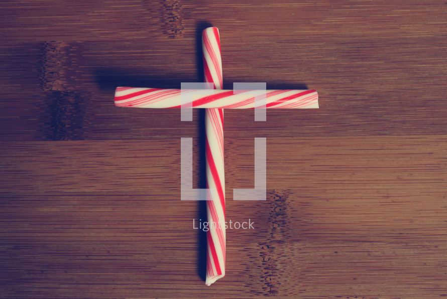 Peppermint sticks formed to make a cross on a wooden table.