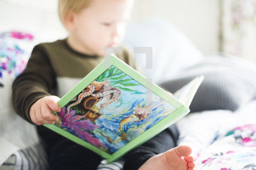 a toddler reading a children's book 