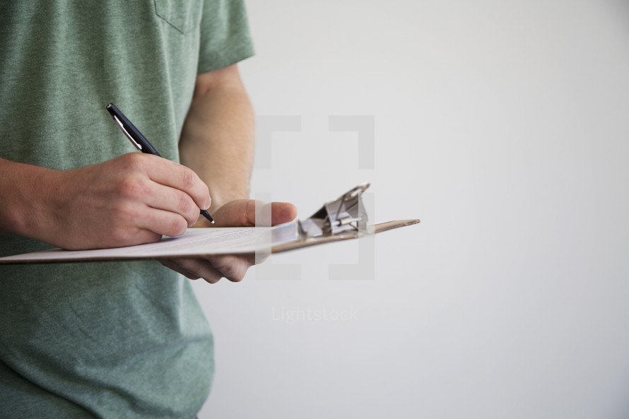 man filling out a form on a clipboard.