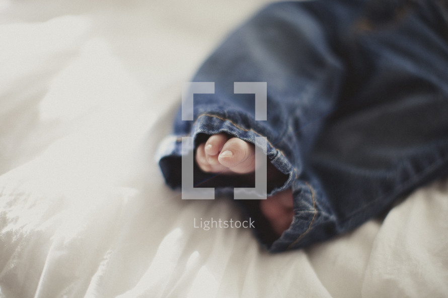 infant feet poking out of denim jeans