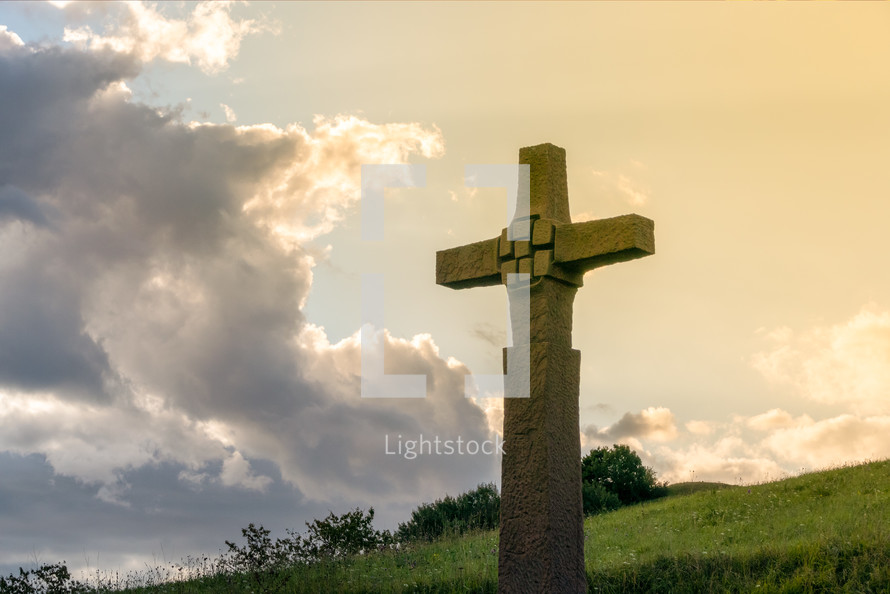 image of a stone cross in front of a dramatic evening sky