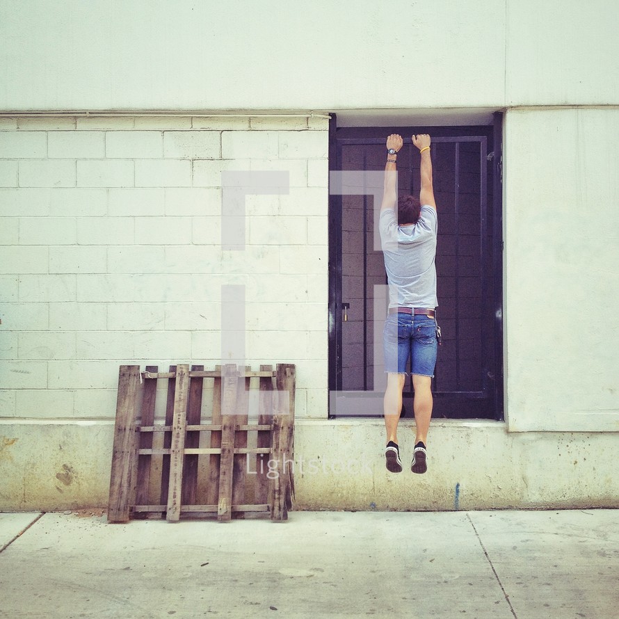 man hanging from a barred door 
