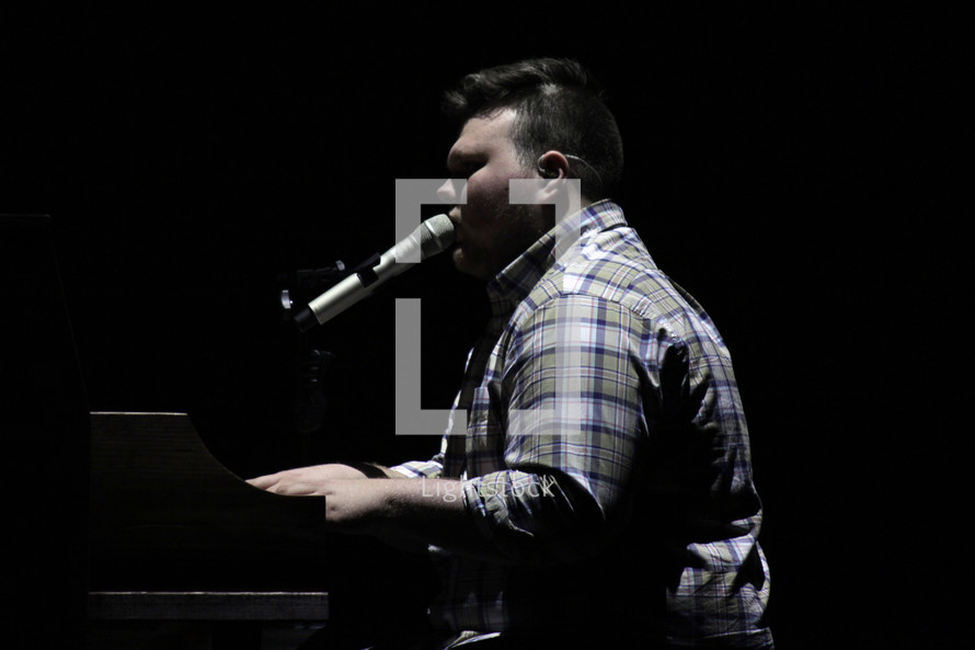 man singing into a microphone and playing a piano 