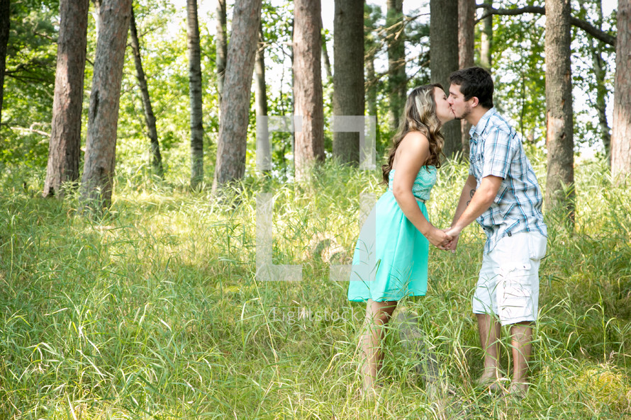 a couple kissing in a forest 