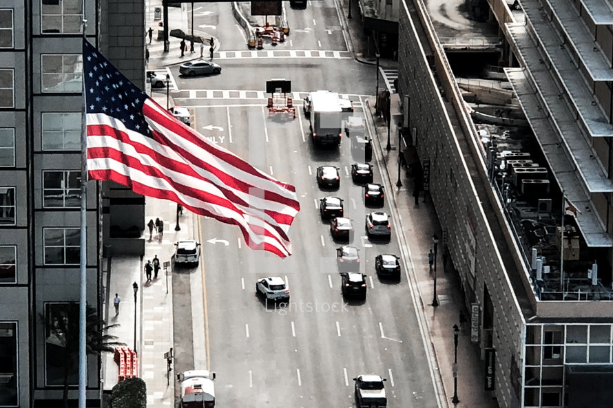 American flag over a city street 