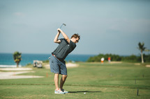 man swinging a golf club on a golf course 