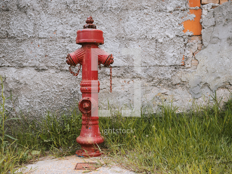 an old fire hydrant in front of a concrete wall