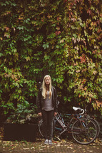woman standing outdoors next to a bicycle 