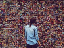 woman looking at a collage of photographs on a wall 