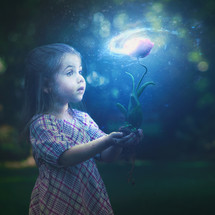 A little girl holds a glowing flower with a bright galaxy