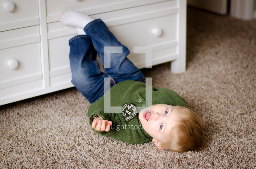 a toddler boy rolling on the floor 
