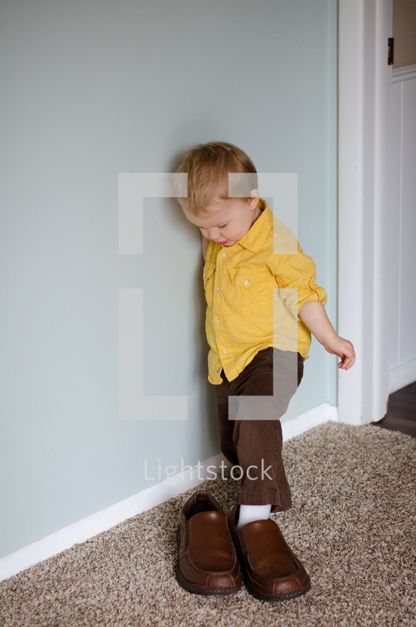 a toddler boy stepping into father's shoes 