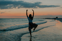 a woman dancing on a beach 