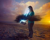 rays of light coming through the clouds as a woman opens a Bible 