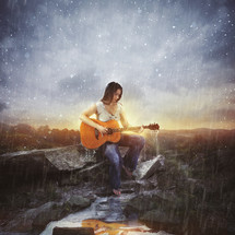 a woman playing a guitar in the rain 