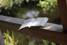 open Bible on a wood railing 
