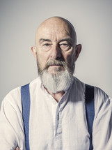 a bald man with a beard in suspenders 