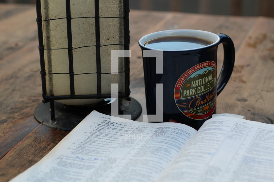 lantern, Bible, and coffee mug on a picnic table at camp 