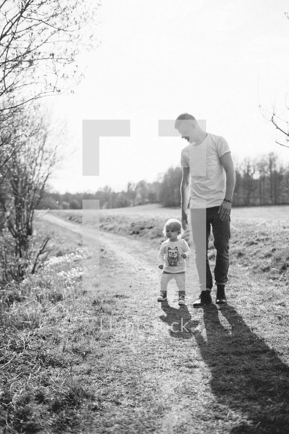Father and child walking on a trail outside.