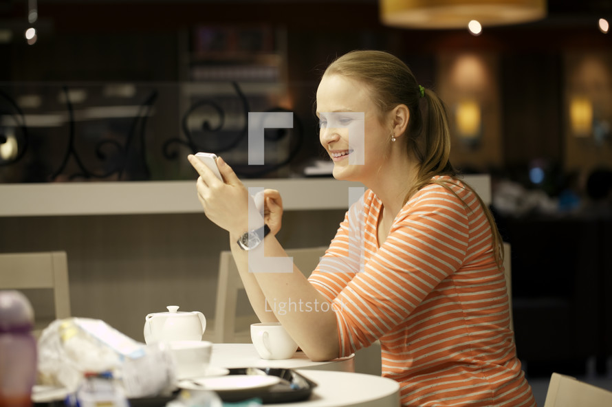 Young woman chatting on smartphone in cafe
