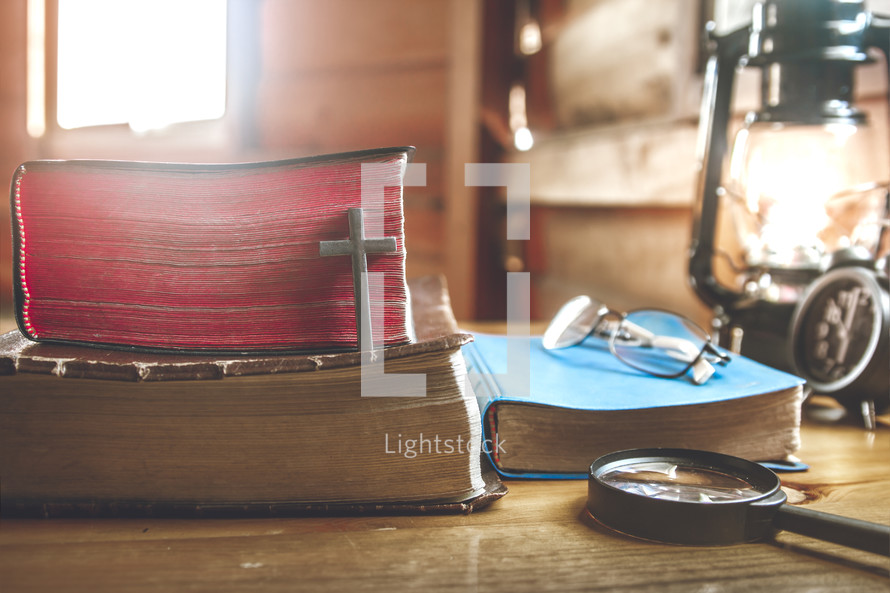 reading glasses and magnifying glass on a stack of Bibles 