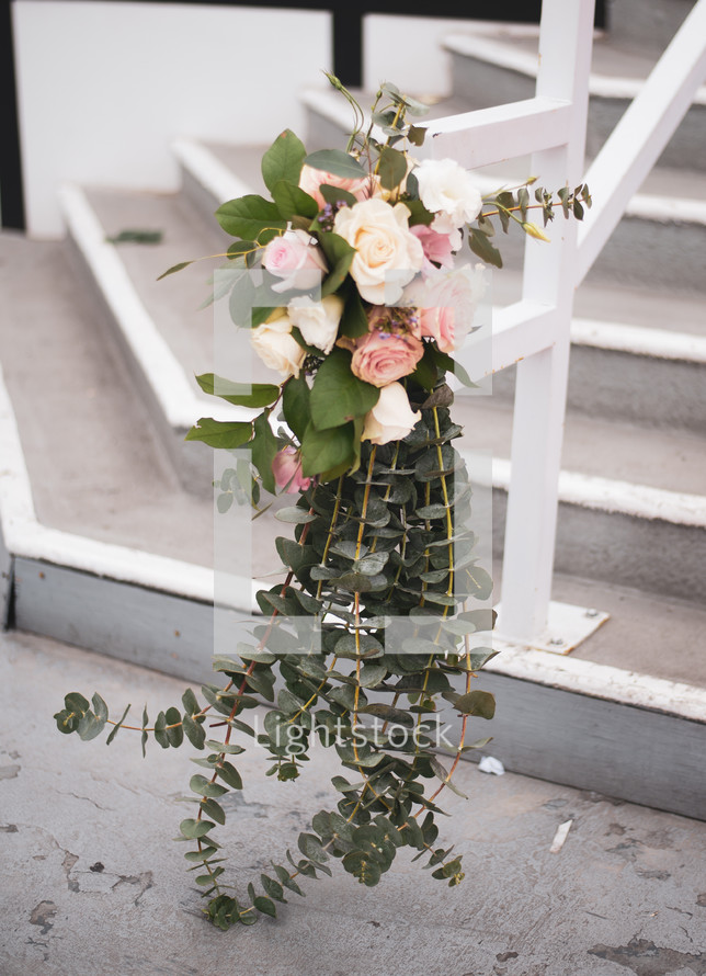 roses and eucalyptus on a railing 