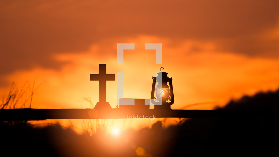 cross, Bible, and oil lamp silhouettes at sunset 
