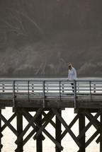 a woman looking over a pier down at the water below 