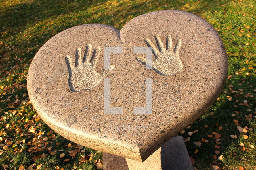 Handprints on a heart shaped table outdoors at a park.