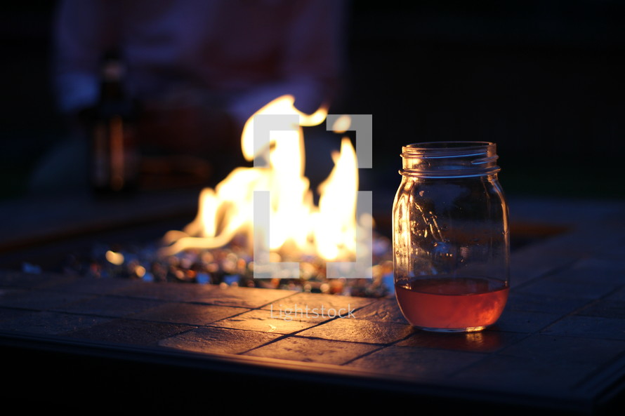 mason jar on the edge of a fire pit 