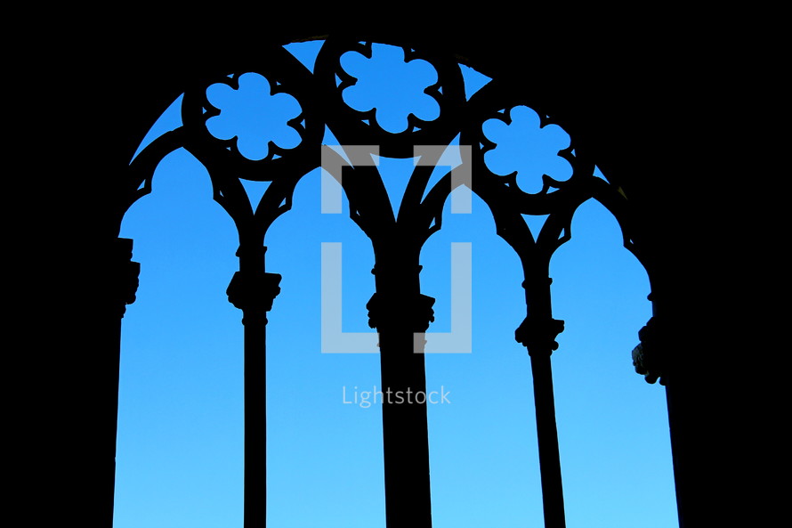 Silhouette of cathedral window frame against a bright blue sky