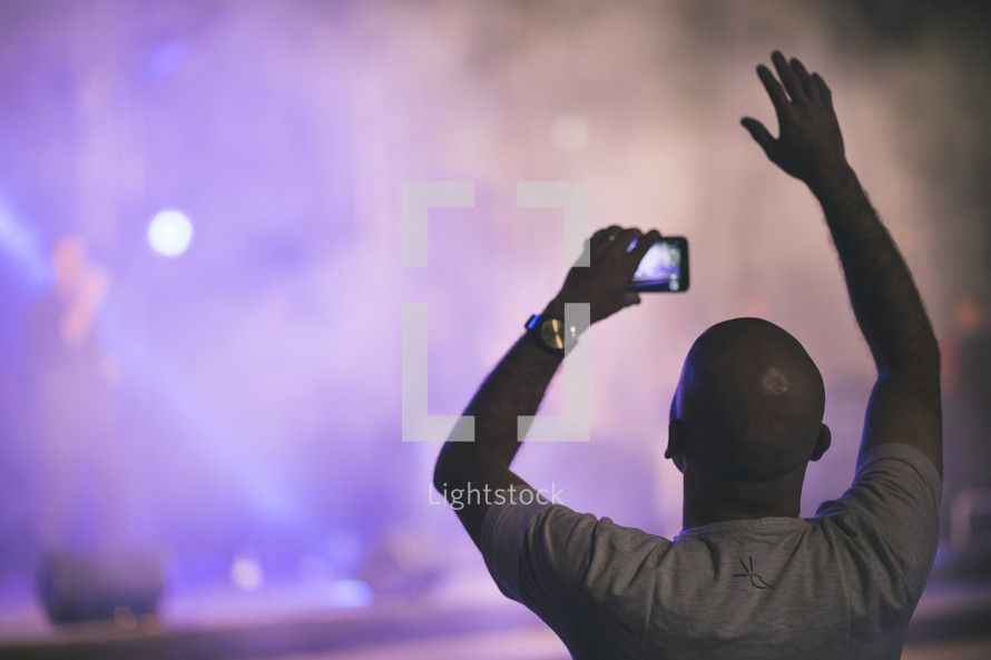 man taking a picture at a concert 