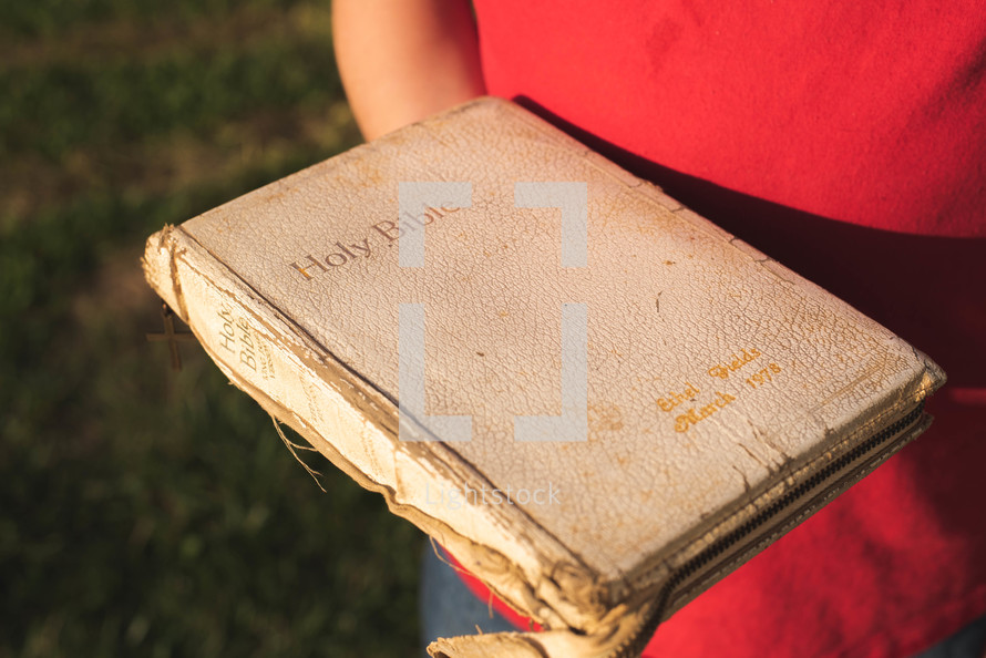person holding a worn Bible 