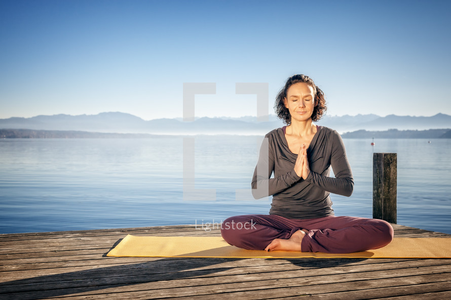 a woman meditating on a dock 