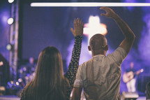 couple with raised hands at a worship service 