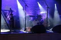 drum set, microphones, and guitars under spot lights on stage 