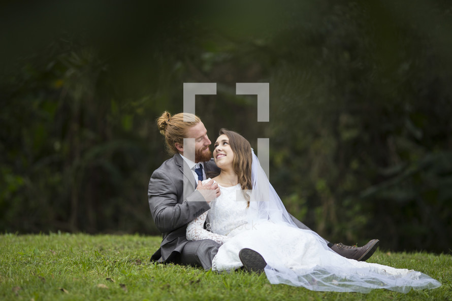 bride and groom embracing sitting in grass 