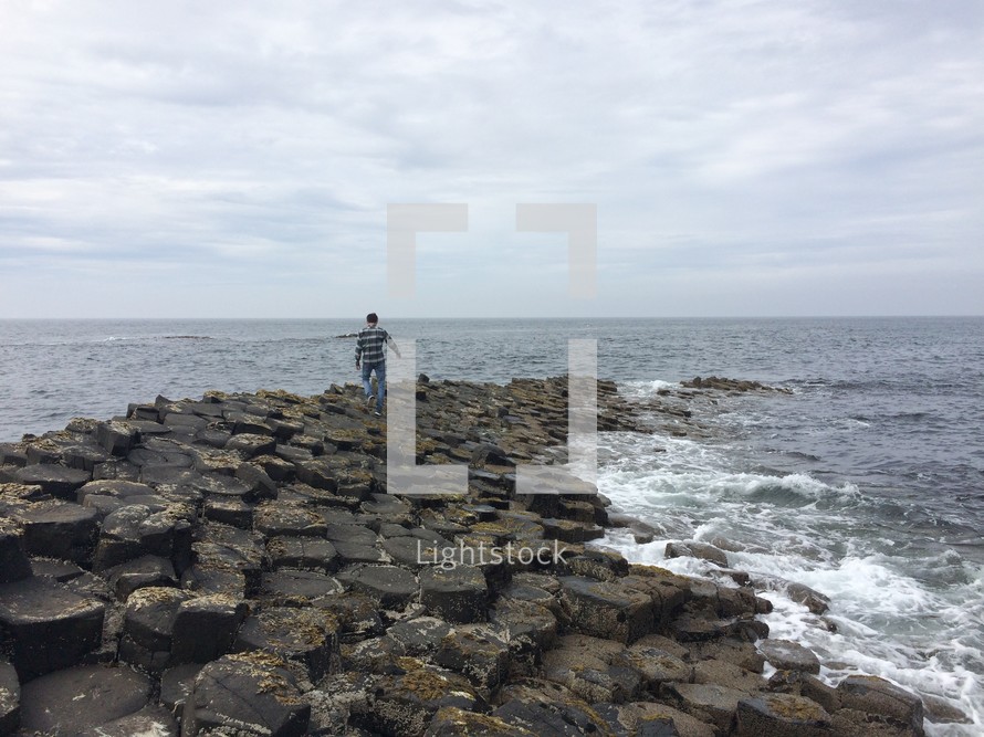 man walking on a rock jetty 