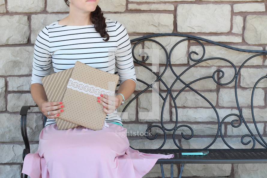 a woman sitting on a bench holding envelopes 