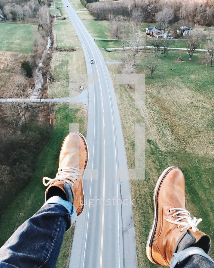 dangling feet and aerial view above a rural highway 