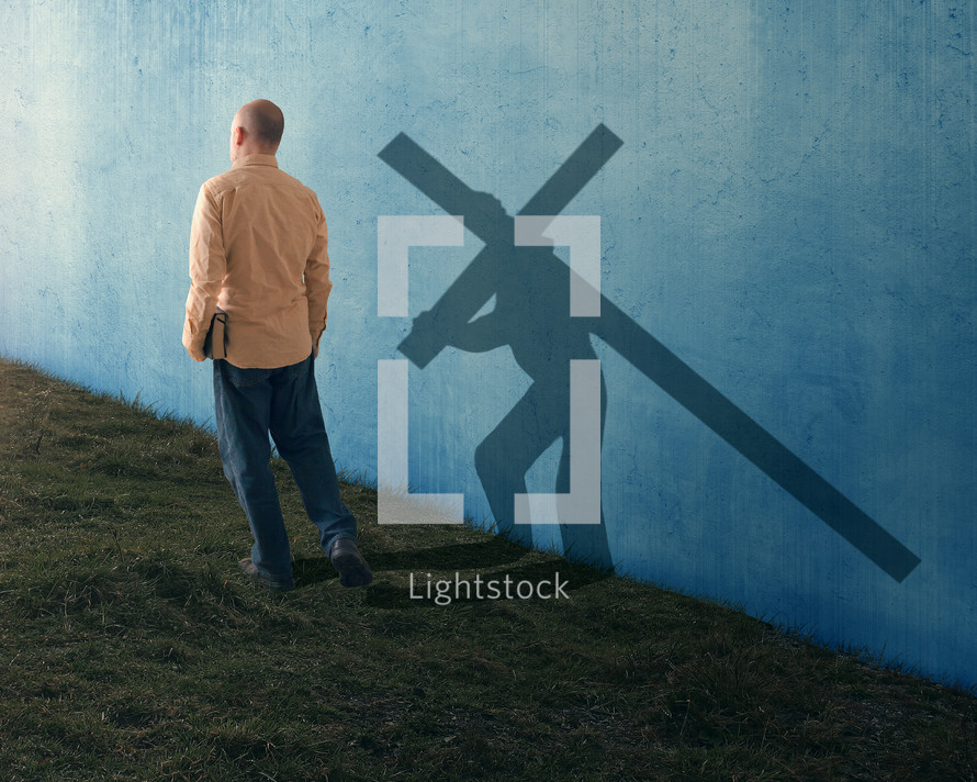 a man carrying a Bible and a shadow of Jesus bearing a cross 