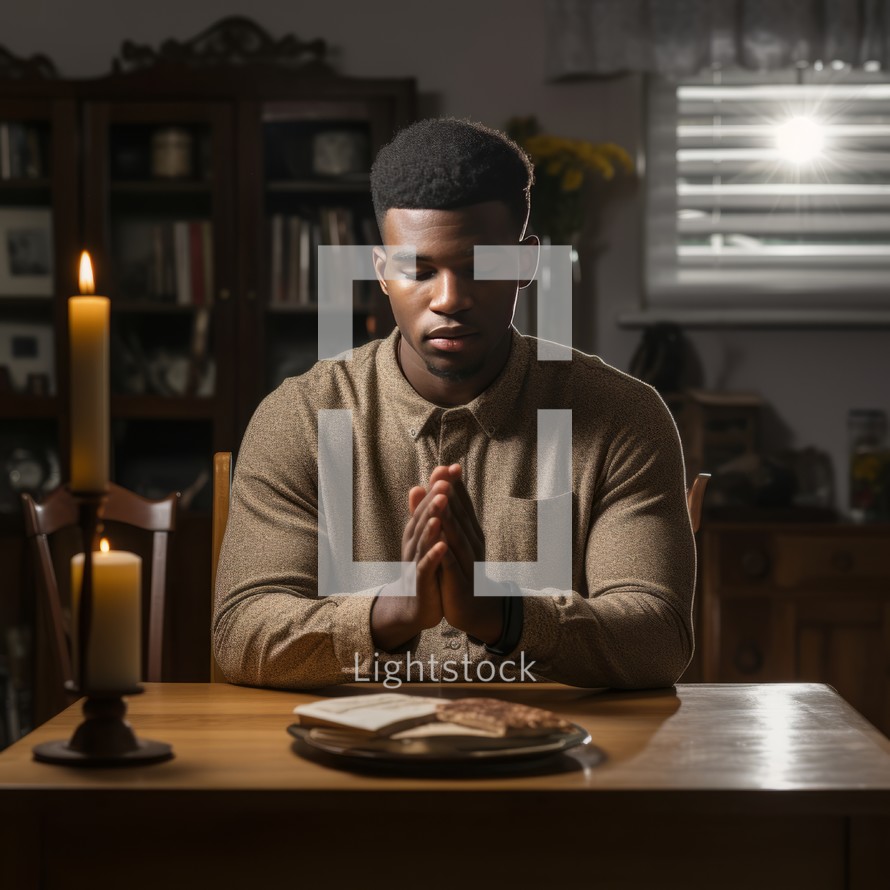 A young man at home, with folded hands in a prayerful gesture, reflecting a moment of personal spirituality and introspection
